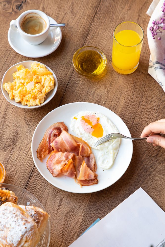 Person reading while eating bacon and eggs at table