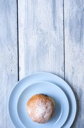 Overhead of jelly doughnut with powdered sugar on blue table