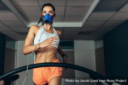 Fit woman running on treadmill with a mask checking her performance 41pLg5