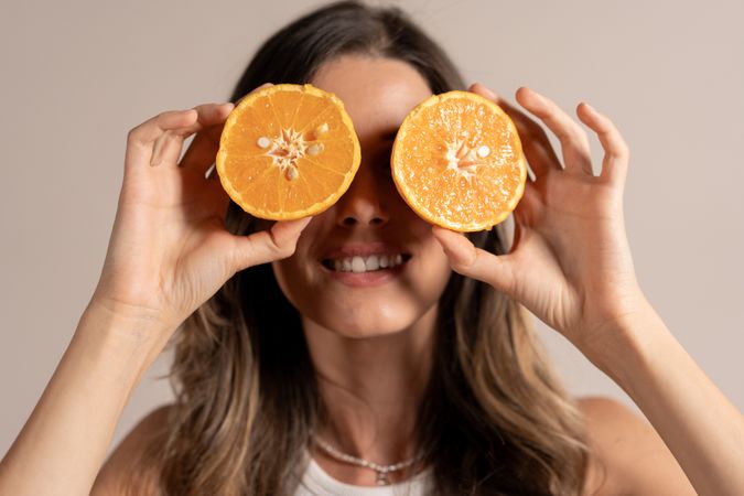 Young woman holding orange slices eyes healthy vitamin natural fruit wellness lifestyle fun happiness energy