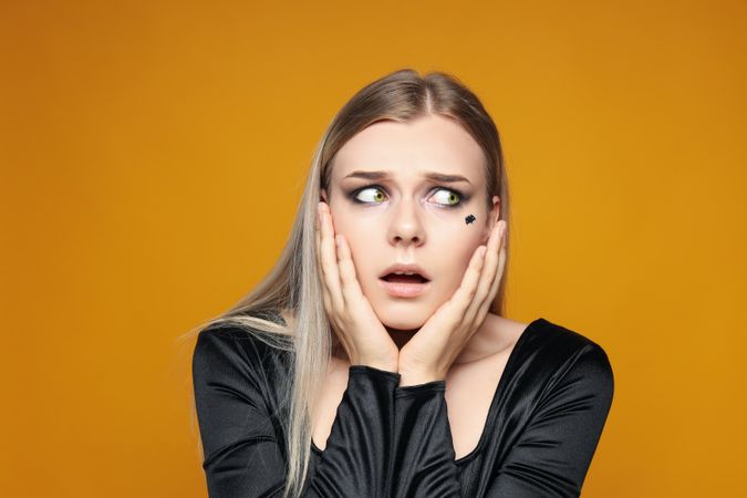 Concept of Halloween, young woman on yellow background