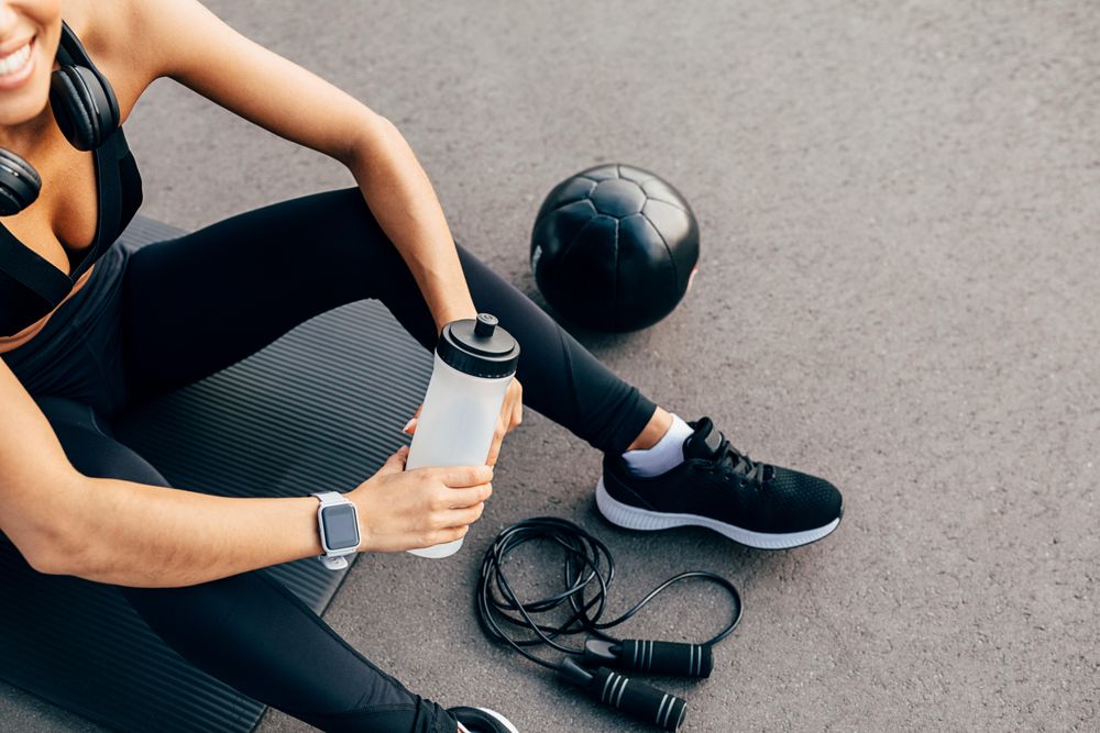 Woman holding water bottle on exercise mat
