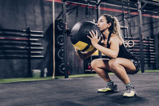 Muscular woman exercising with ball in gym