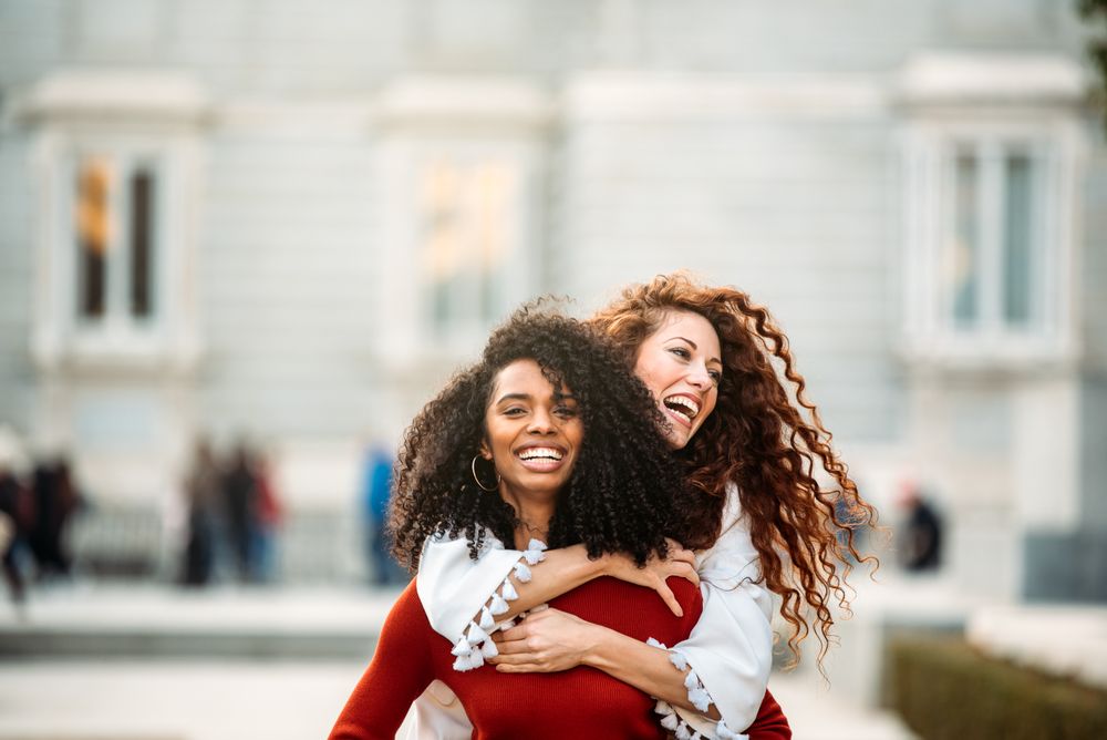 Two cheerful young women playing piggy back