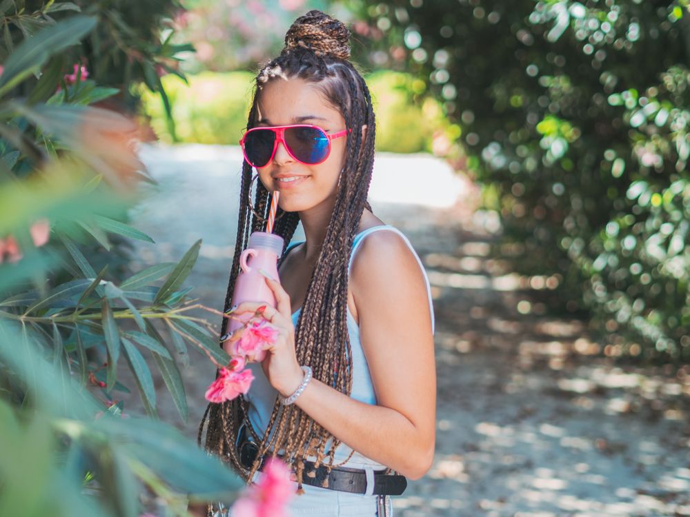 Stylish young woman with dreadlocks and beverage