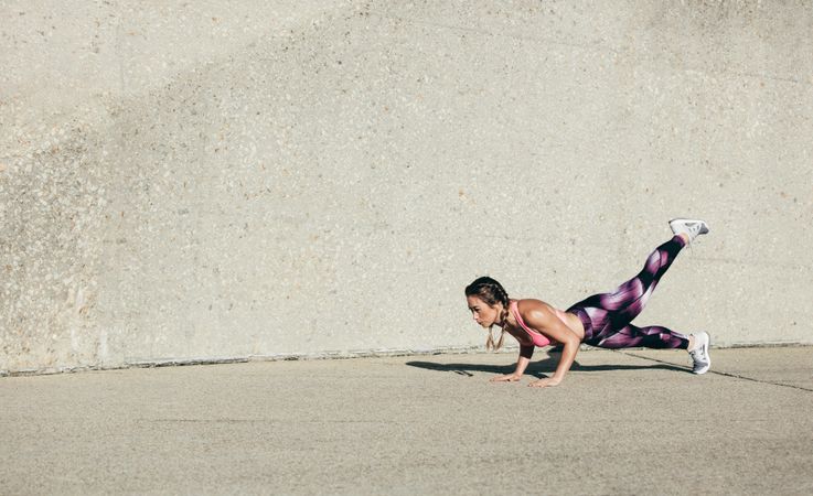 Fit female doing press-ups during the training outdoors