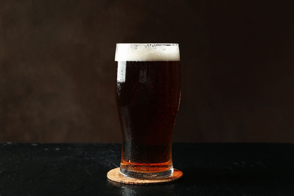 Glass of beer on table against brown background