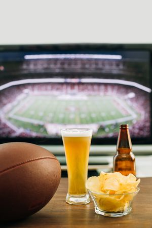 Beer and snacks prepared for watching american football on TV