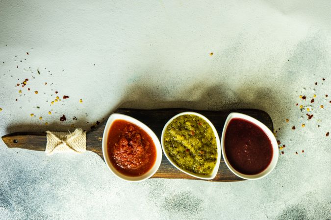 Top view of three flavorful spicy traditional Georgian sauces on wooden board with copy space