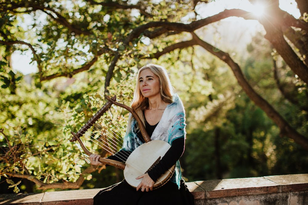 Cheerful charming woman with lyre in garden