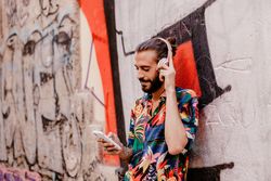 Smiling man listening to music and using smartphone