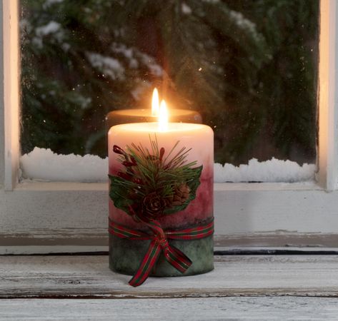 Christmas candle glowing on window sill