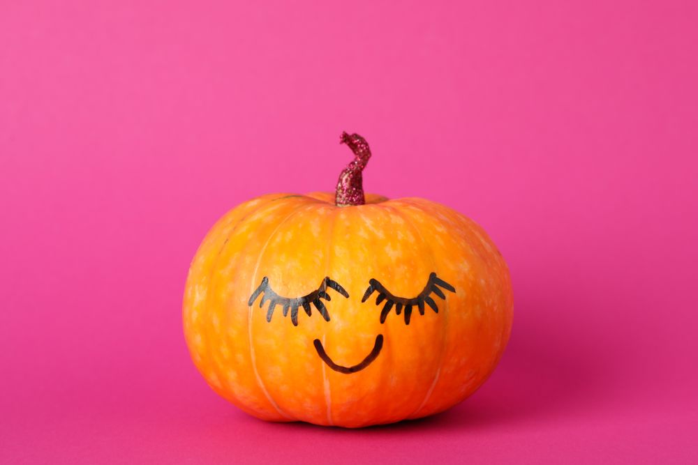 Pumpkin with smile on pink background, space for text