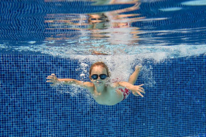 Active boy swimming in clear pool water