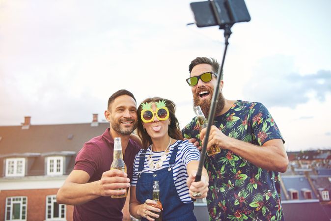 Group of friends with selfie stick, woman in center sticking her tongue out