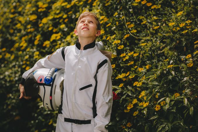 Boy in space suit with helmet walking outdoors and looking up