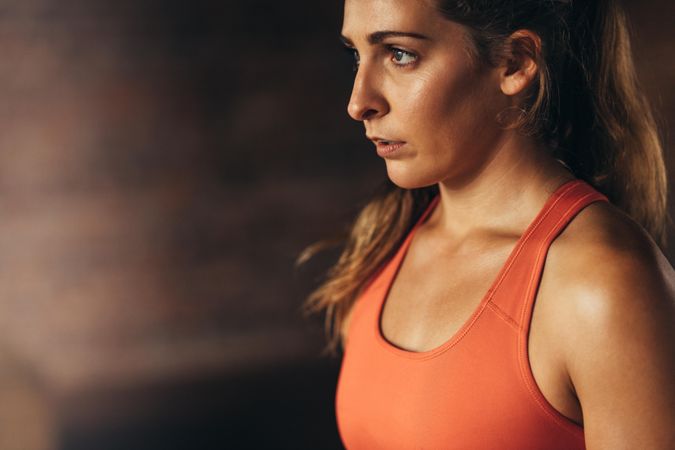 Close up of young woman in orange sports bra looking away