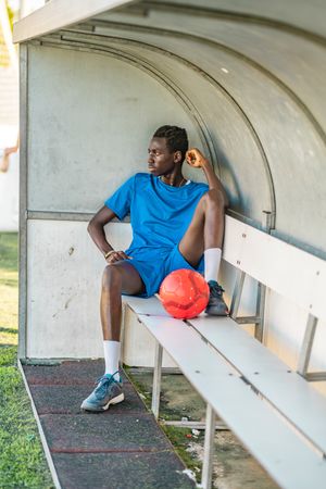 Black football player resting on bench