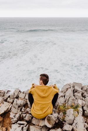 Person in yellow hoodie on stony shore