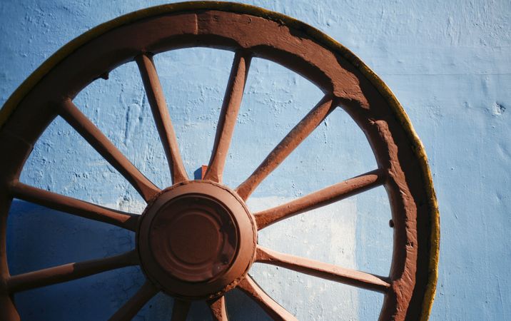 Close up of old iron wheel on blue wall