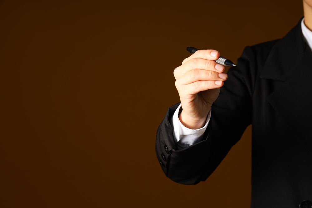 A man in a suit holds a pen