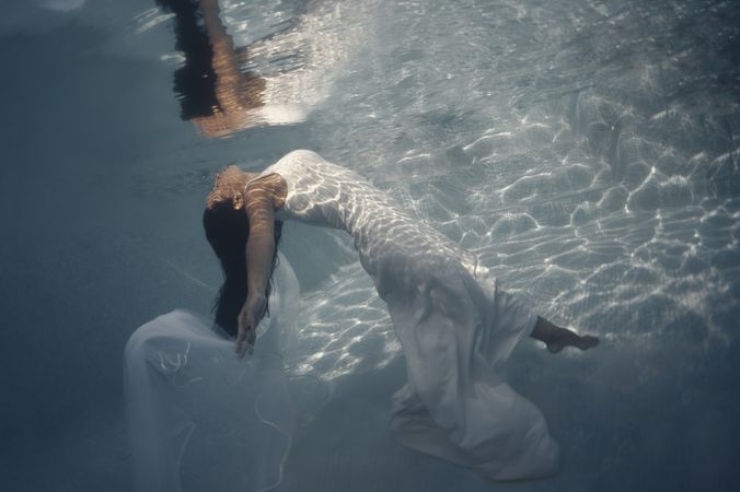 Woman in wedding dress floating underwater