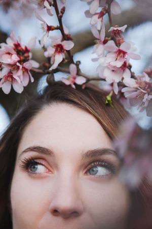 Young woman near tree twig with flowers