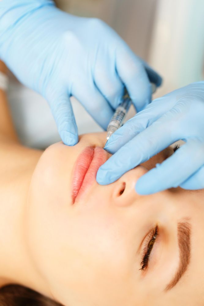 Hands in latex gloves providing injectable beauty treatment for client, vertical