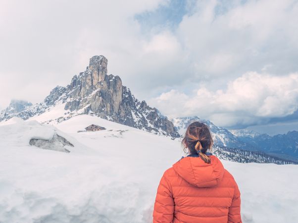 Woman in warm jacket looking at snowy mountain landscape
