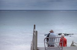 Two tourists in sun hats walking down to the Indian Ocean