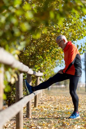 Man stretching legs on wooden fence