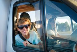 Delighted kid enjoying road trip in summertime