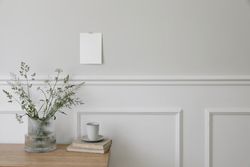 Empty paper taped on wall mockup above wooden desk with vase and branches