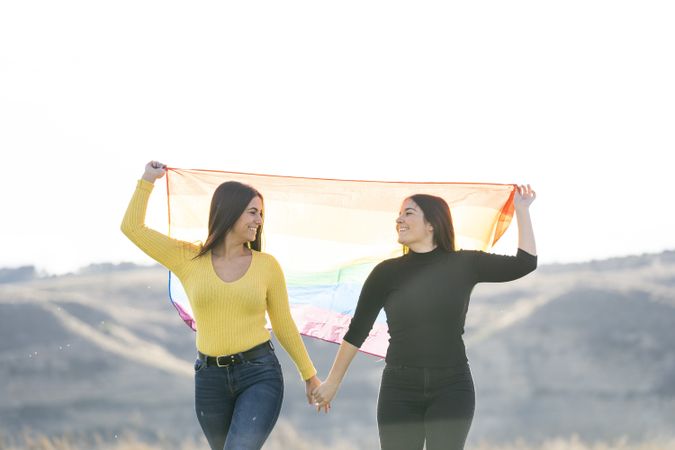 Young female couple with gay flag