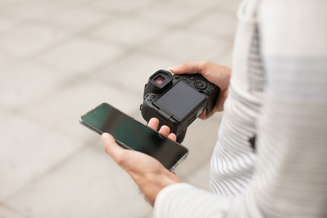 A young man transfers photos from his camera to his smartphone