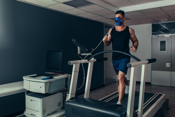 Male runner with mask running on treadmill machine testing his performance