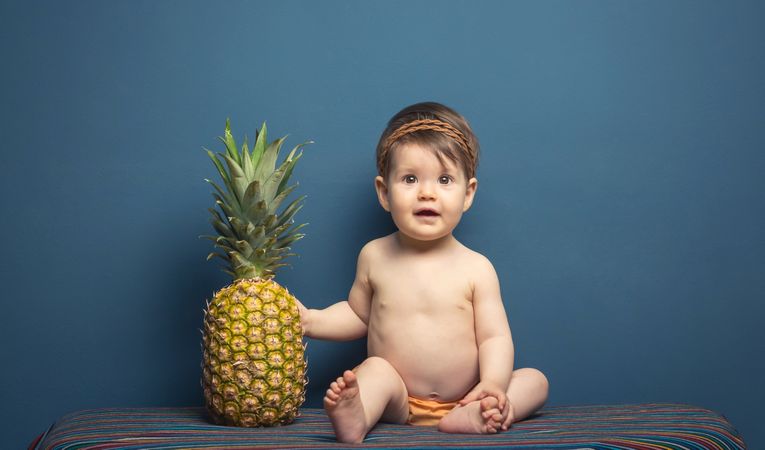 Happy baby playing with a pineapple