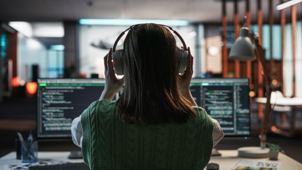Creative Office: Professional Female Programmer Uses Headphones, Working on Desktop Computer.