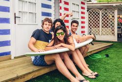 Young friends holding woman on top of surfboard