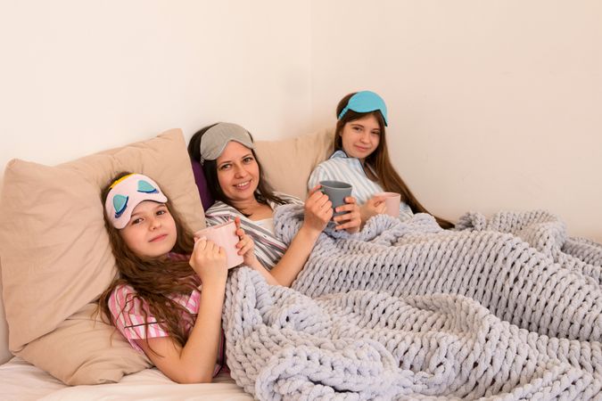 Family morning ritual with coffee and joyful expressions in bed.