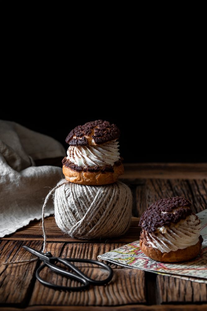 Delicious choux buns and wool threads on wooden table