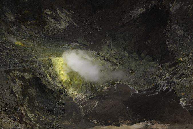 View of Lokon volcano crater, yellow sulfides and toxic gases emanating from the ground, Indonesia