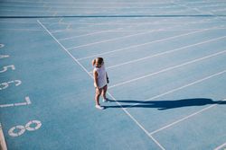 Young woman looking out at the lanes from the beginning of a track field