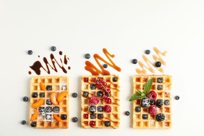 Flat lay composition with waffles and different toppings, top view