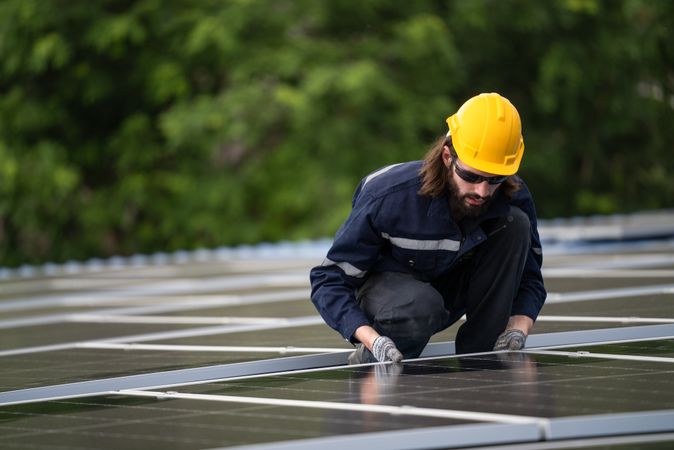 Male engineer checking solar cell  or photovoltaic cell by electronic device installed on the roof of the factory. Technician worker repair or inspect the system. Industrial renewable energy concept