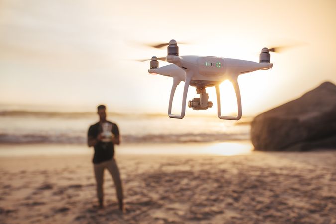 Young man on the seashore flying a drone
