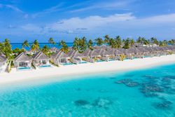 Holiday villas line the beach in the Maldives, with copy space