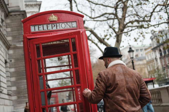 Adult man walking into a telephone box