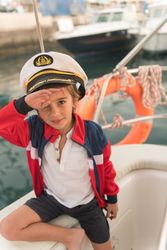 Child sitting on deck of yacht near quay