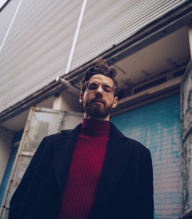 Handsome young white male model with hip glasses, beard and turtleneck near building